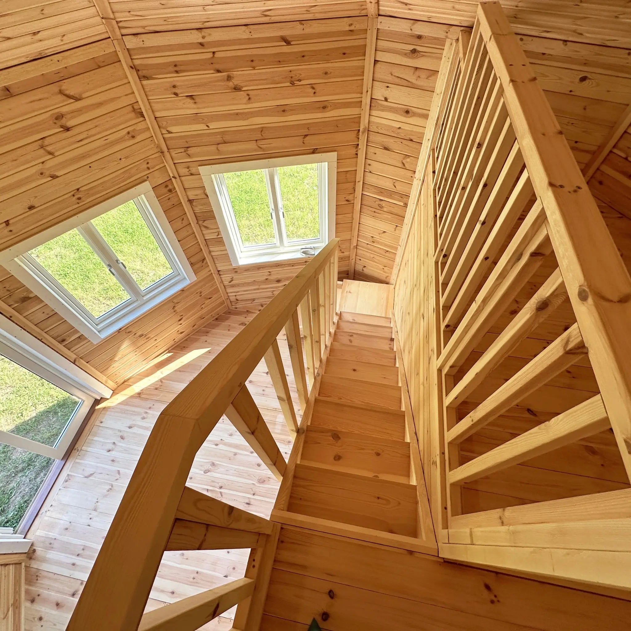 Downward view from loft staircase in the Altura Loft Cabin revealing timber steps and window-lined walls