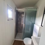 Compact bathroom with shower and toilet inside the Archwood shepherd’s hut