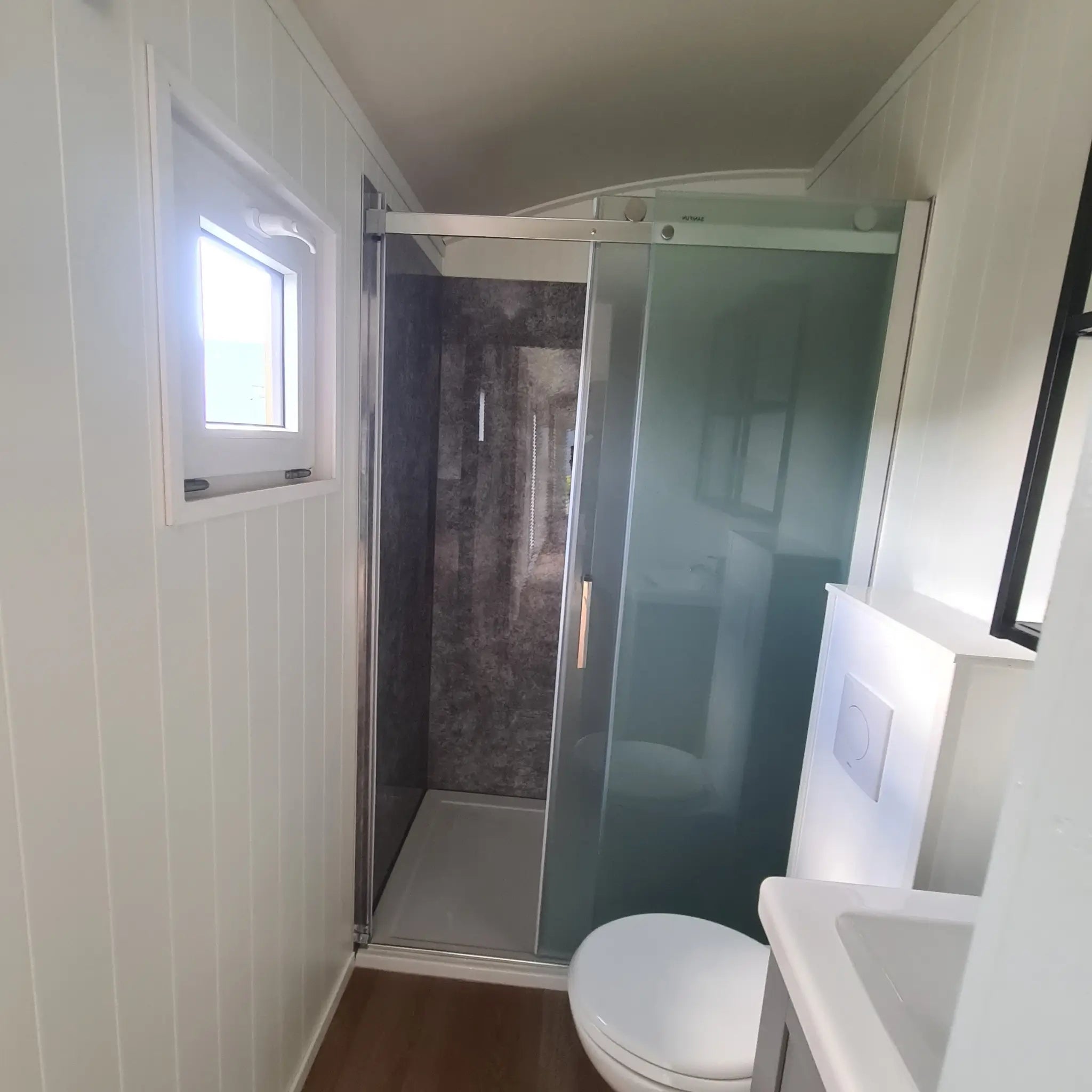 Compact bathroom with shower and toilet inside the Archwood shepherd’s hut
