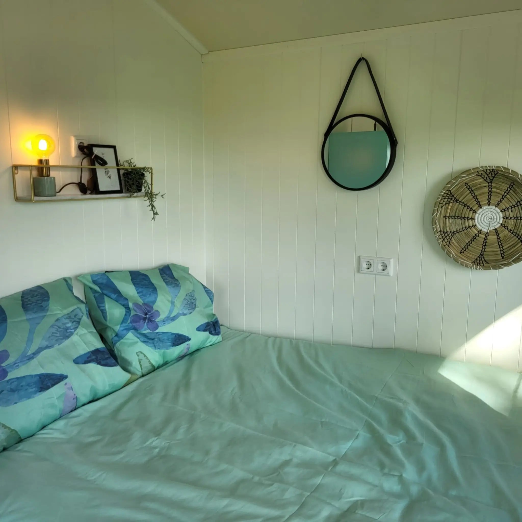 Bedroom detail with decorative wall mirror inside the Archwood shepherd’s hut