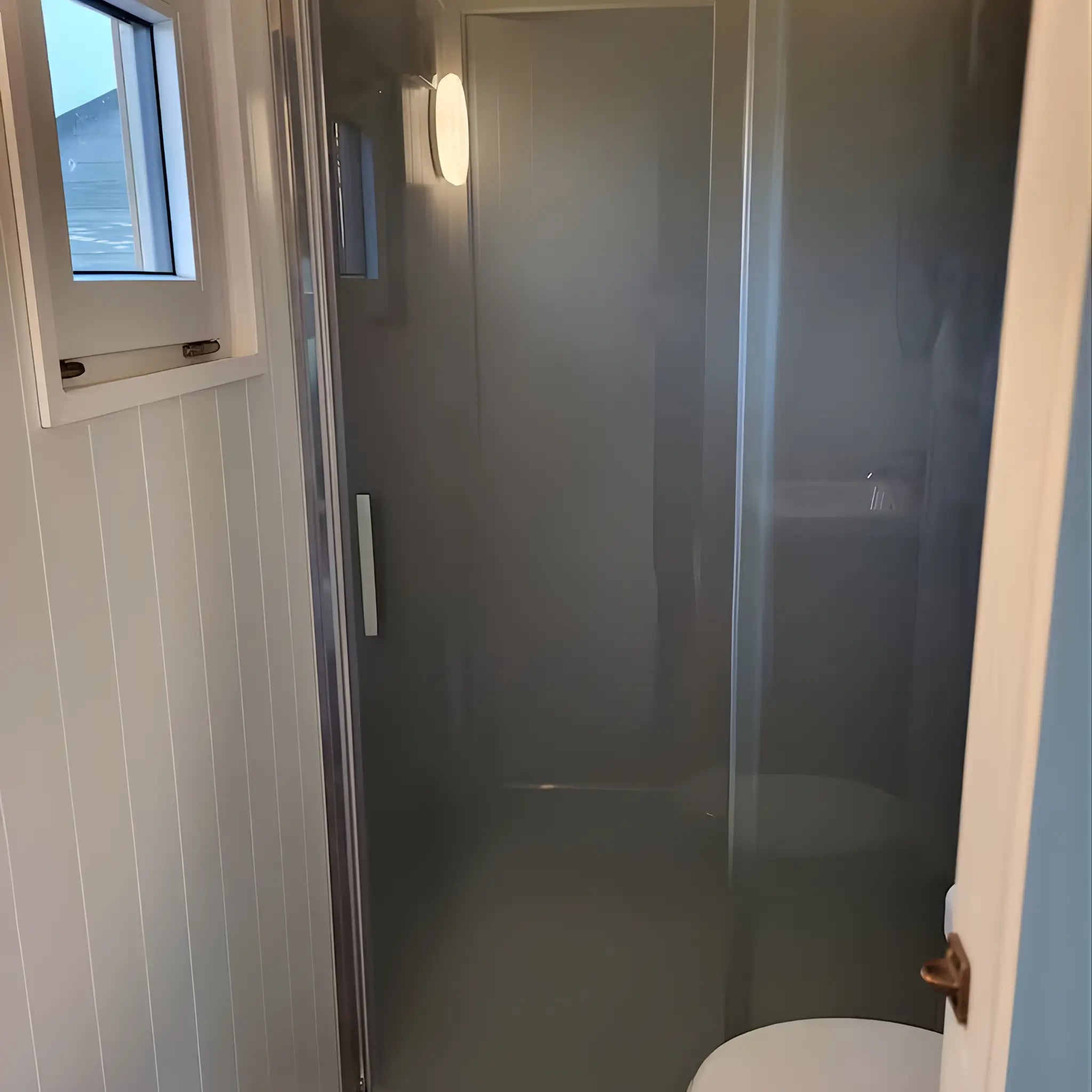 Shower enclosure inside the Archwood glamping shepherd’s hut bathroom