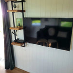 Close up of wall mounted TV and decorative shelves in the Archwood shepherd’s hut