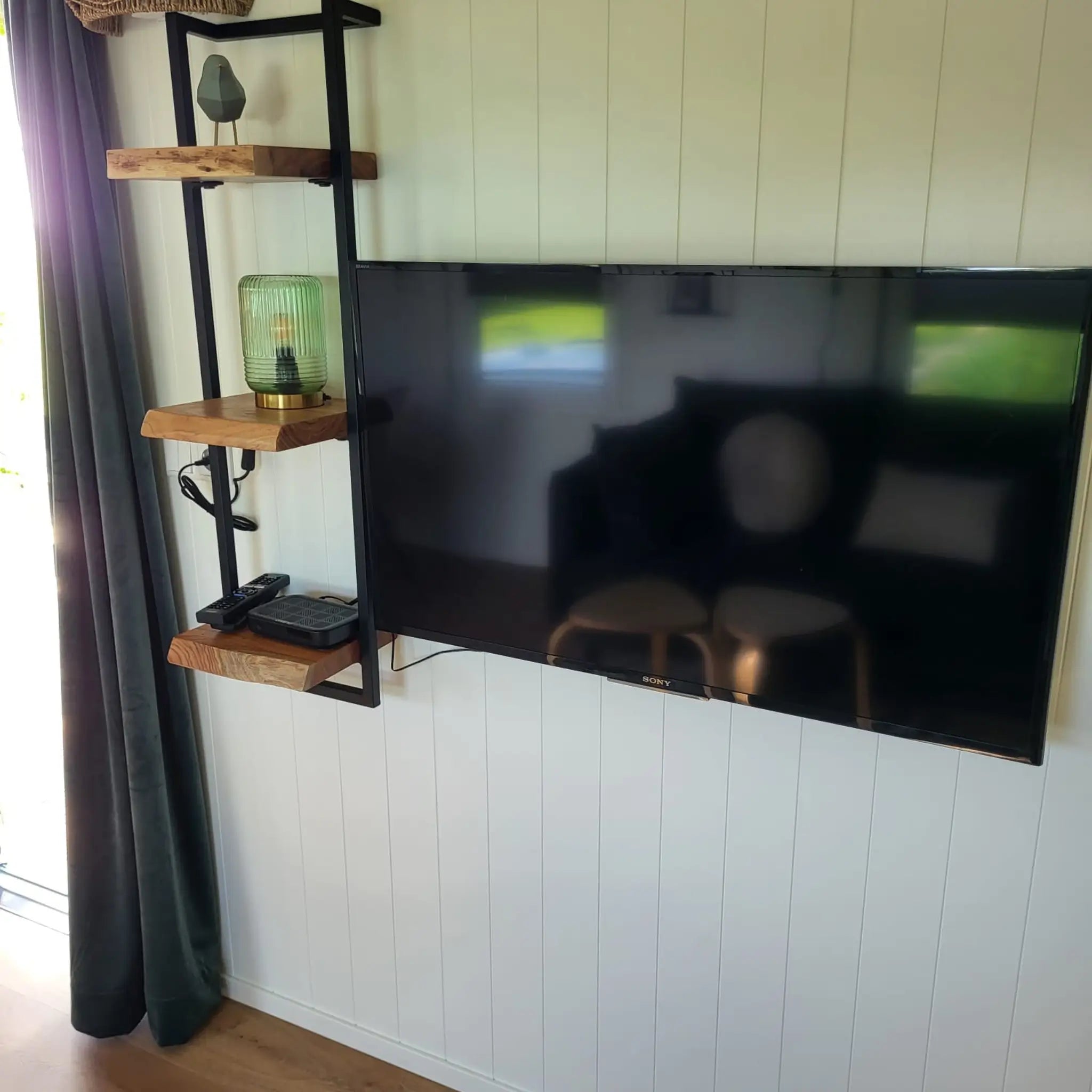 Close up of wall mounted TV and decorative shelves in the Archwood shepherd’s hut