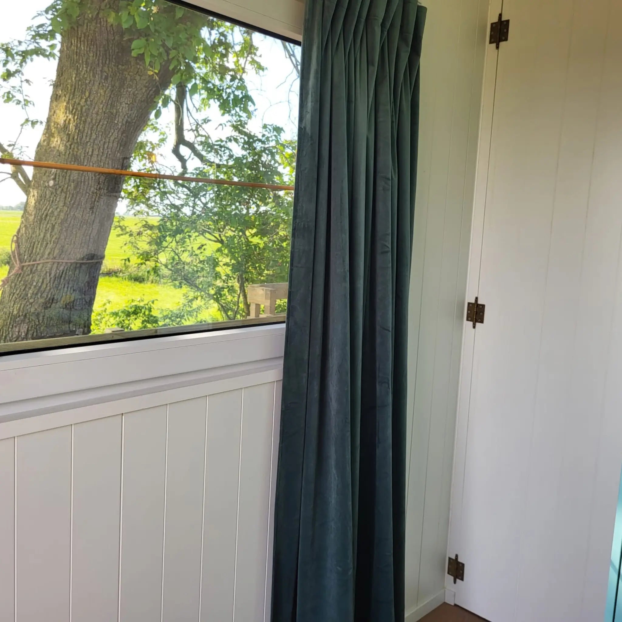 Window view from inside the Archwood shepherd’s hut overlooking countryside