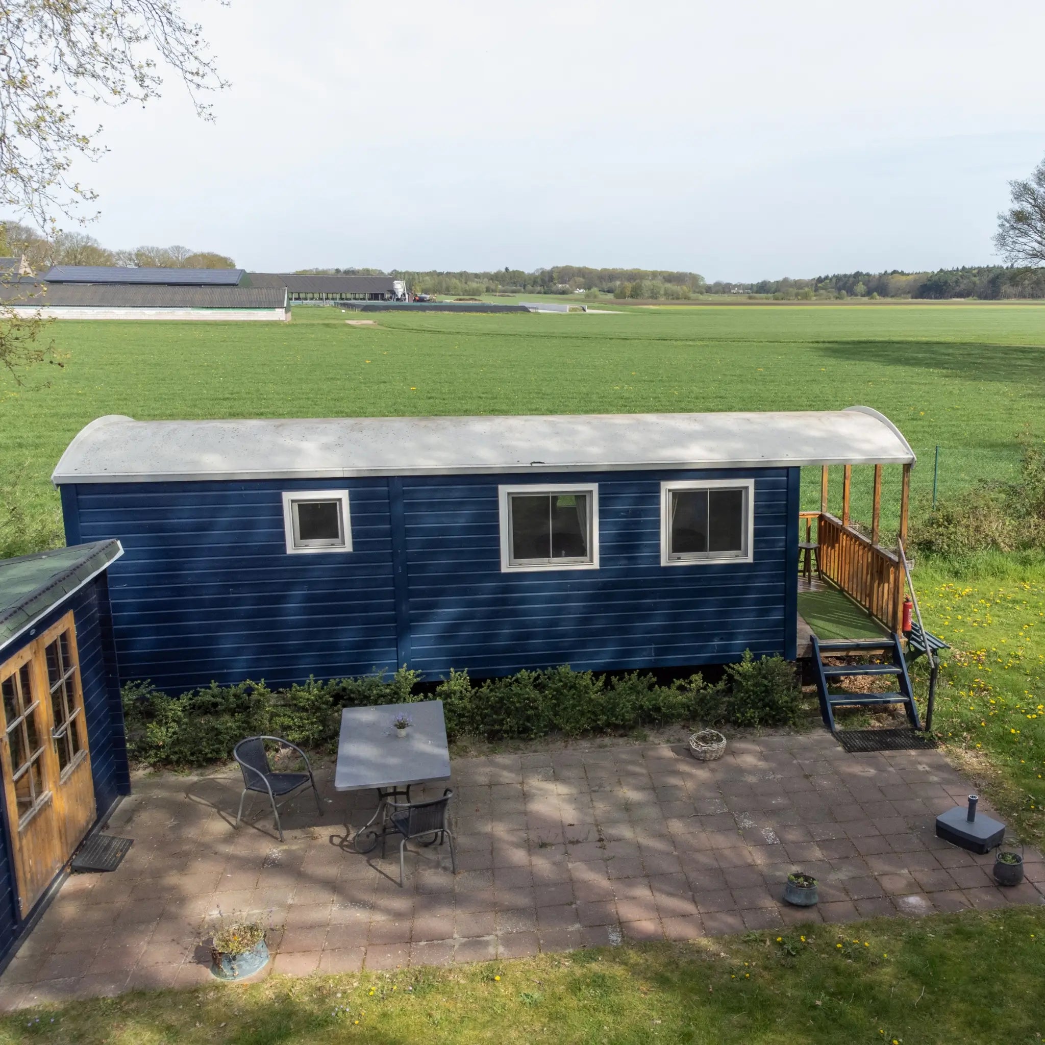 Side exterior view of a modern shepherd’s hut with patio space
