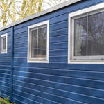 Blue timber cladding and side windows on a luxury shepherd’s hut