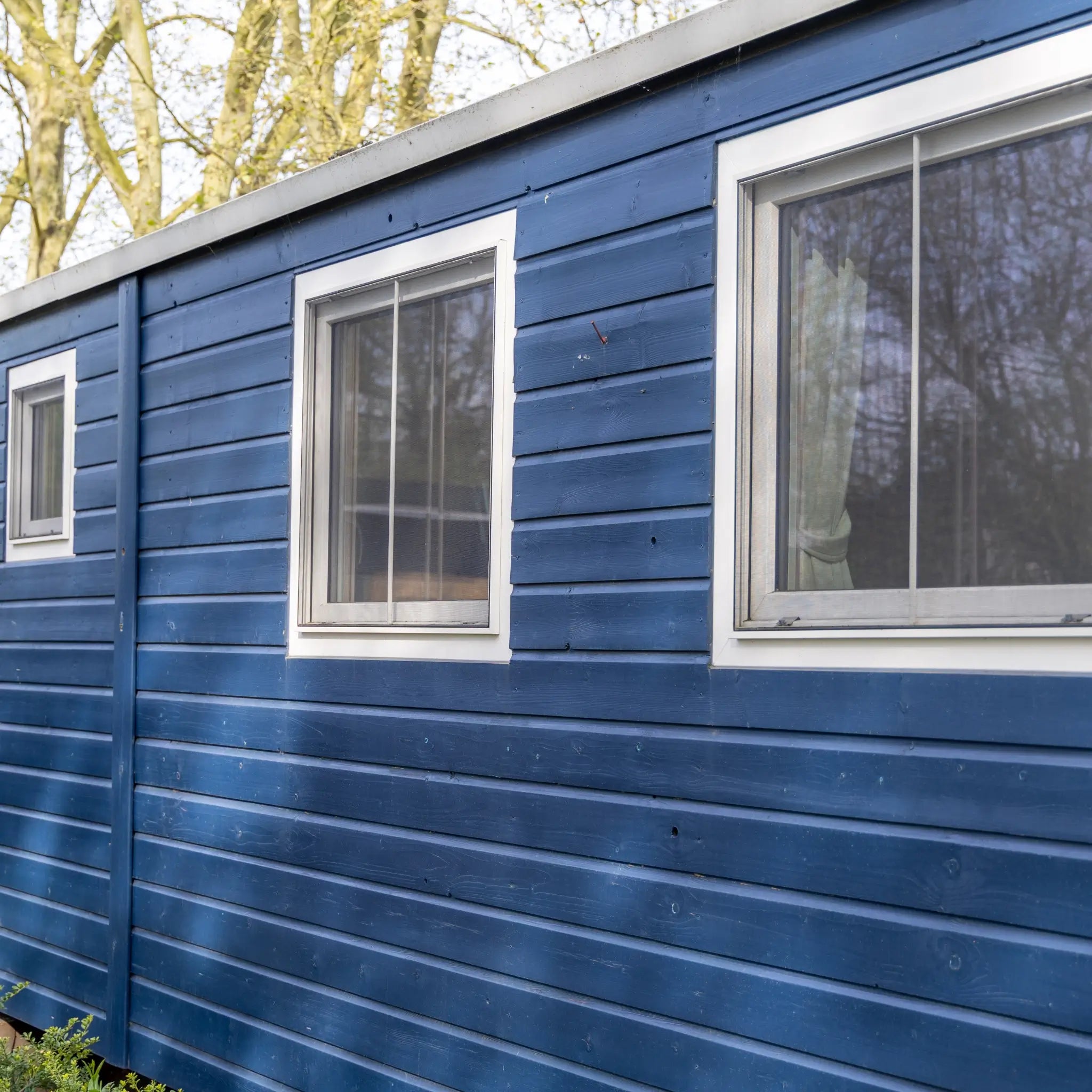 Blue timber cladding and side windows on a luxury shepherd’s hut