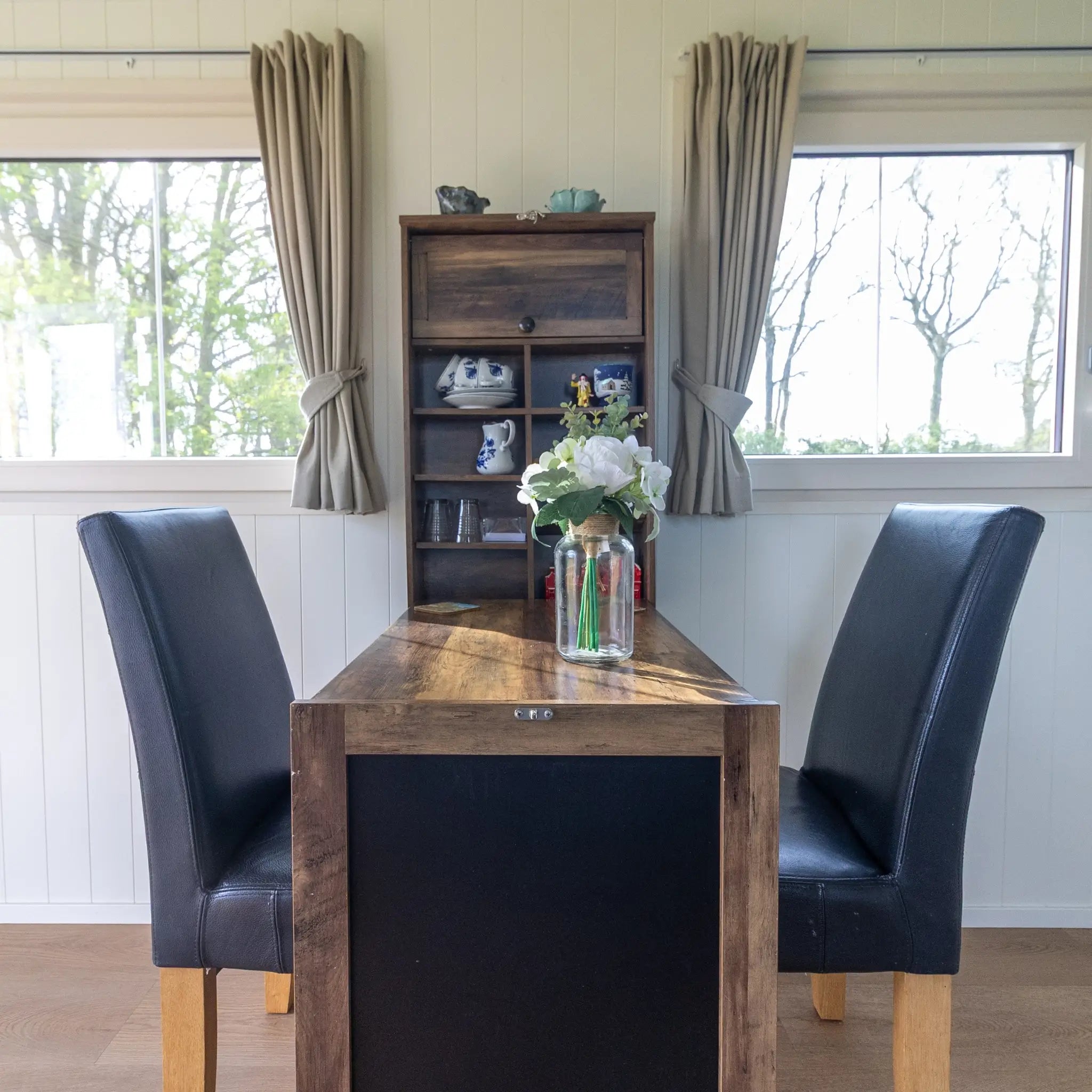 Wooden dining table and seating area inside a modern shepherd’s hut interior