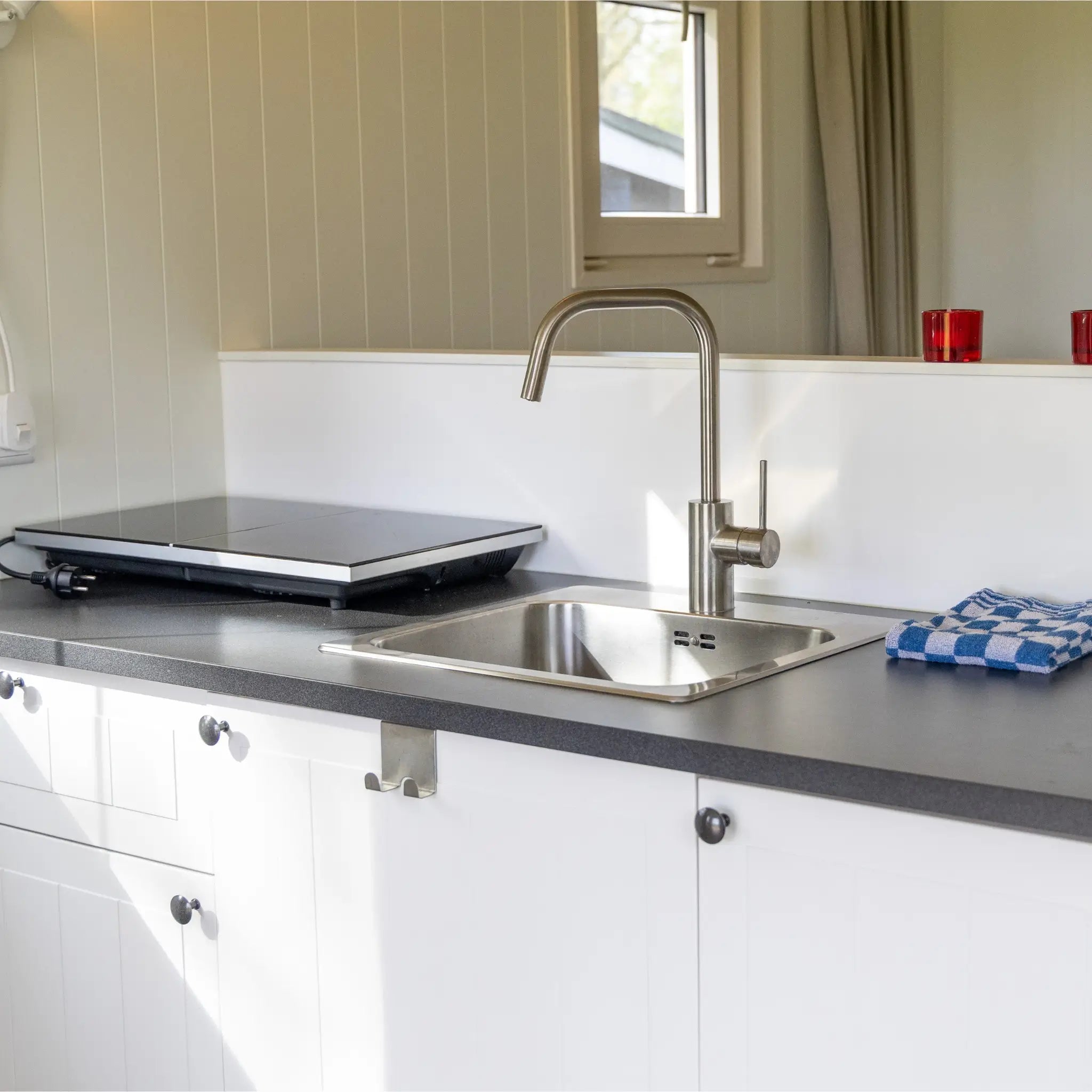 Compact kitchenette with sink and electric hob inside a glamping shepherd’s hut