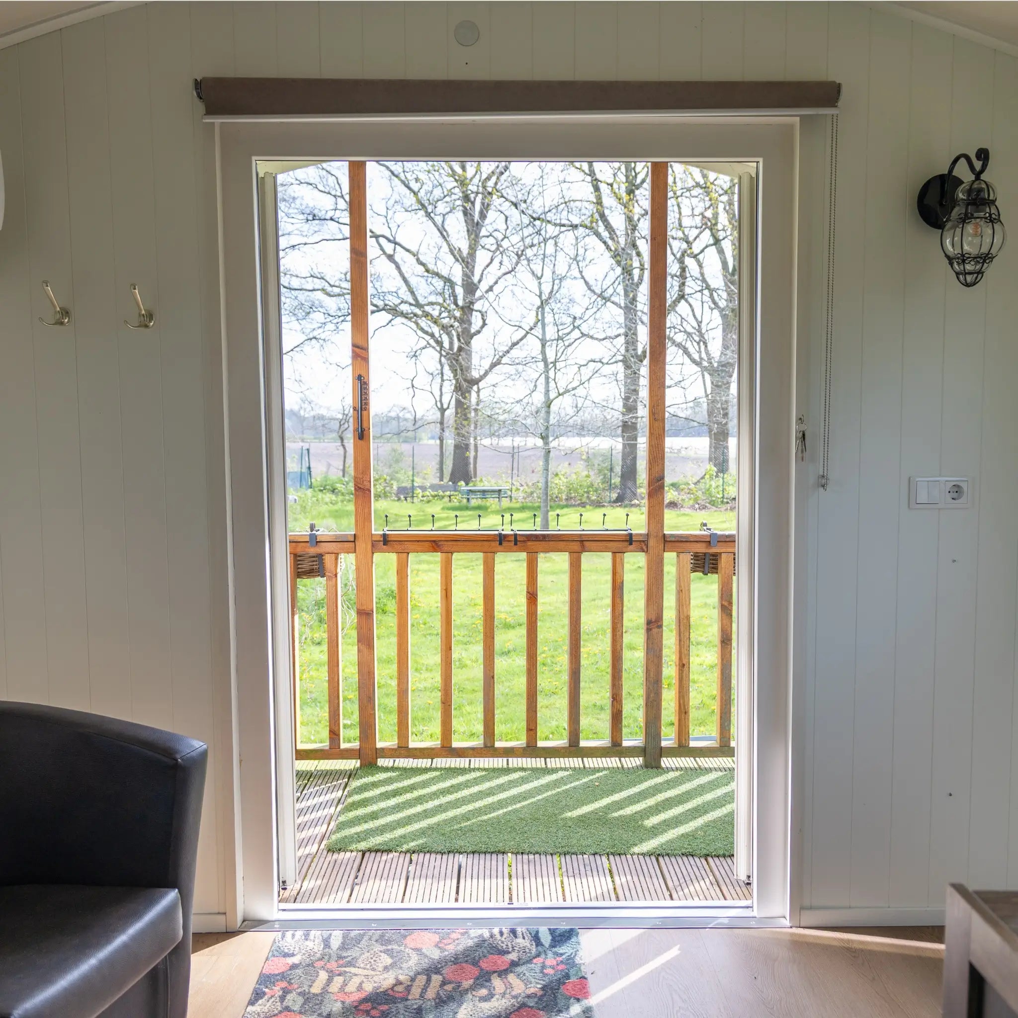 View from inside a shepherd’s hut looking out onto private decking and countryside