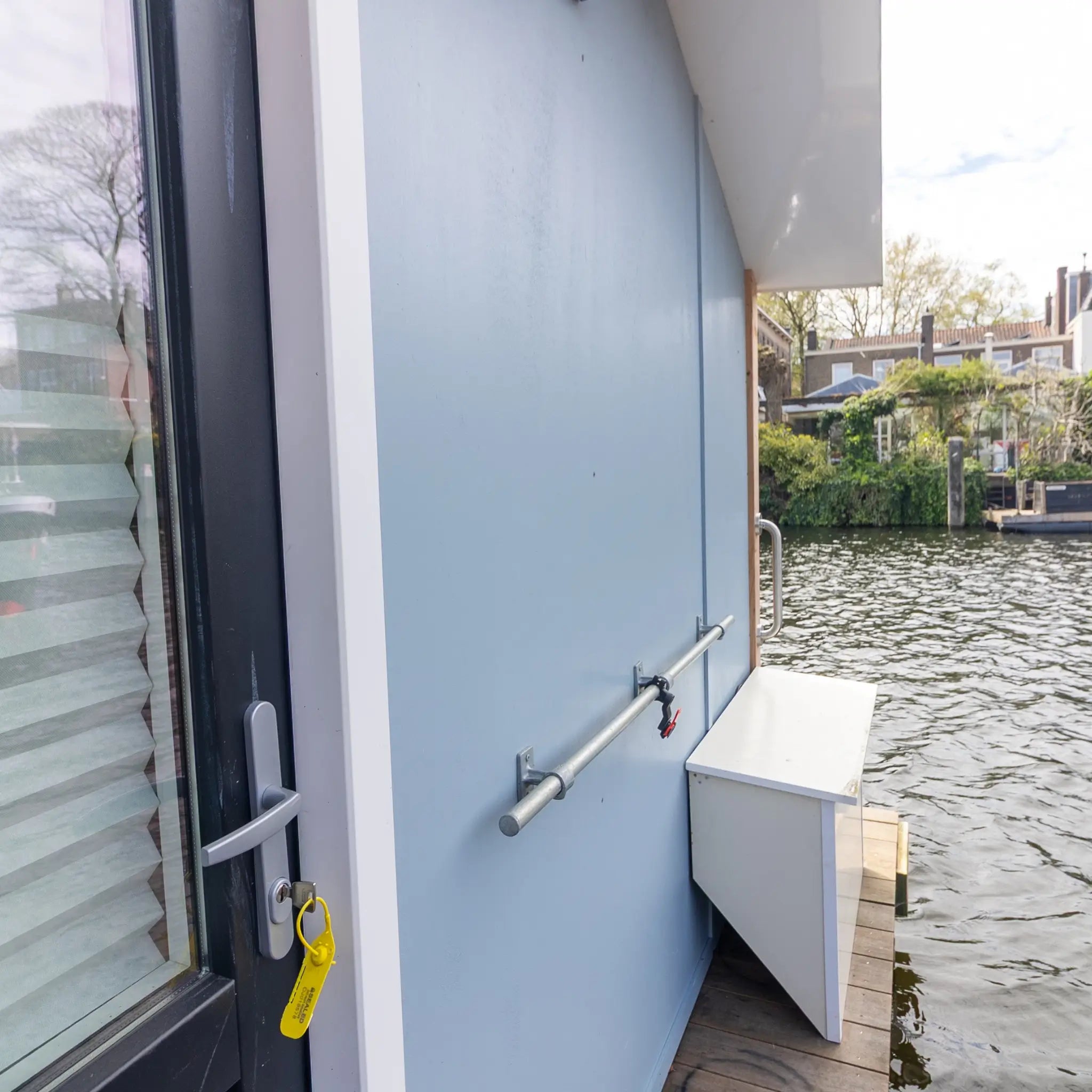Back exterior view of a 2 person floating shepherd’s hut with waterside deck, rear access door and canal mooring setting.