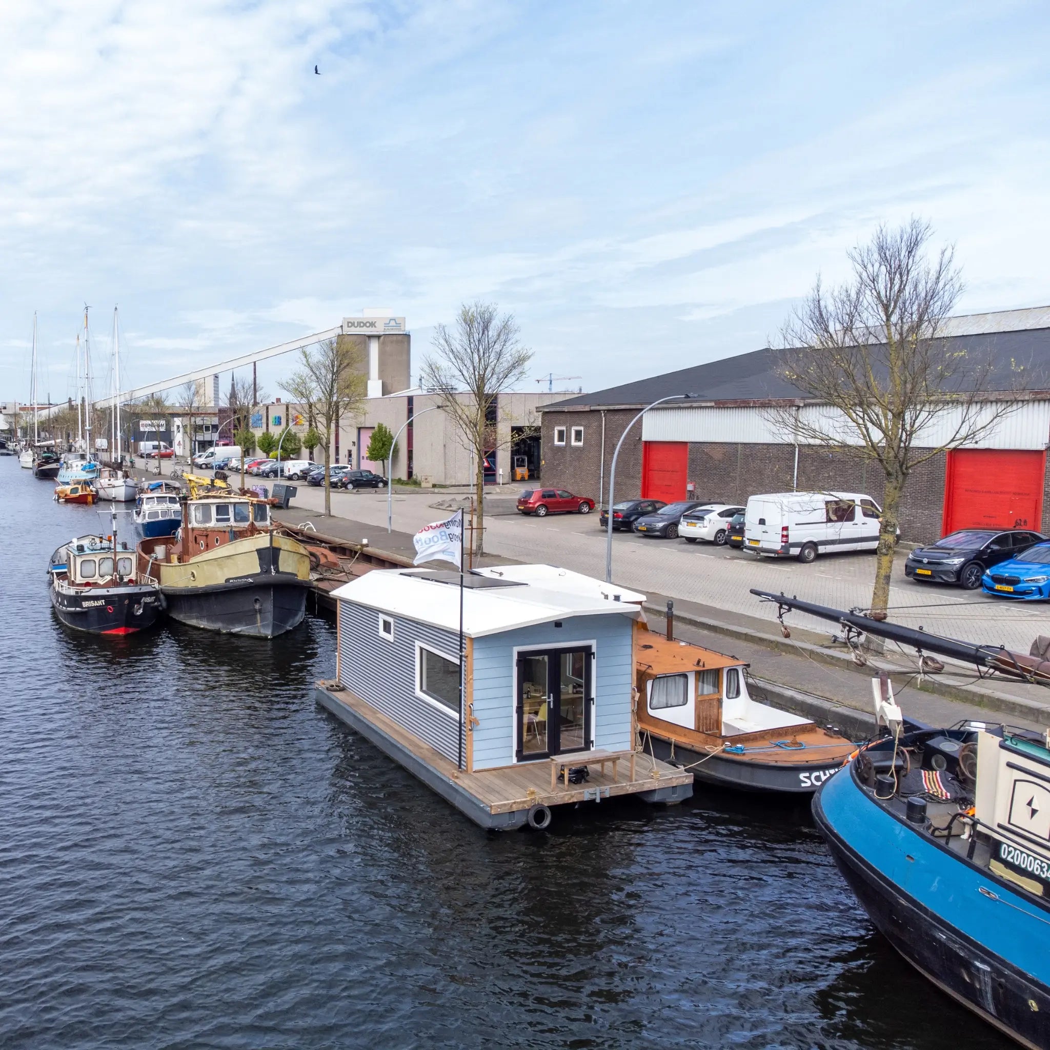 Front view of a modern floating shepherd’s hut moored along an urban canal marina.