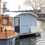 Rear exterior close-up of a floating shepherd’s hut with back door, storage box and floating deck platform.