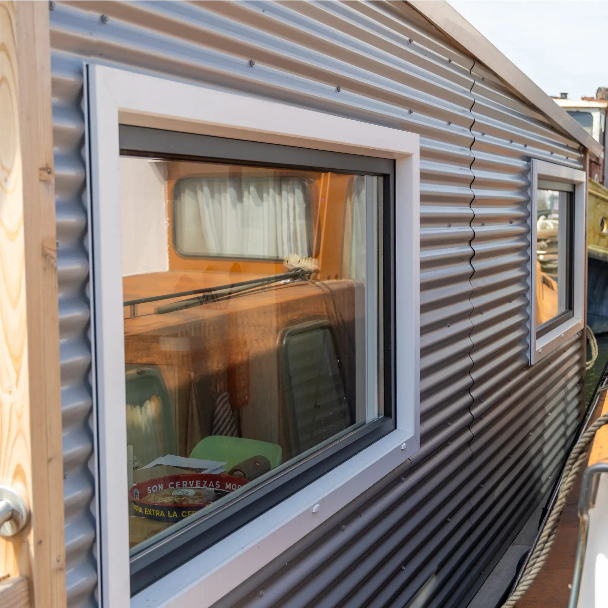 Close-up of side windows on a floating shepherd’s hut with contemporary cladding and canal reflections.