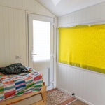 Interior rear entrance of a floating shepherd’s hut with compact bedroom, natural light and cosy cabin styling.