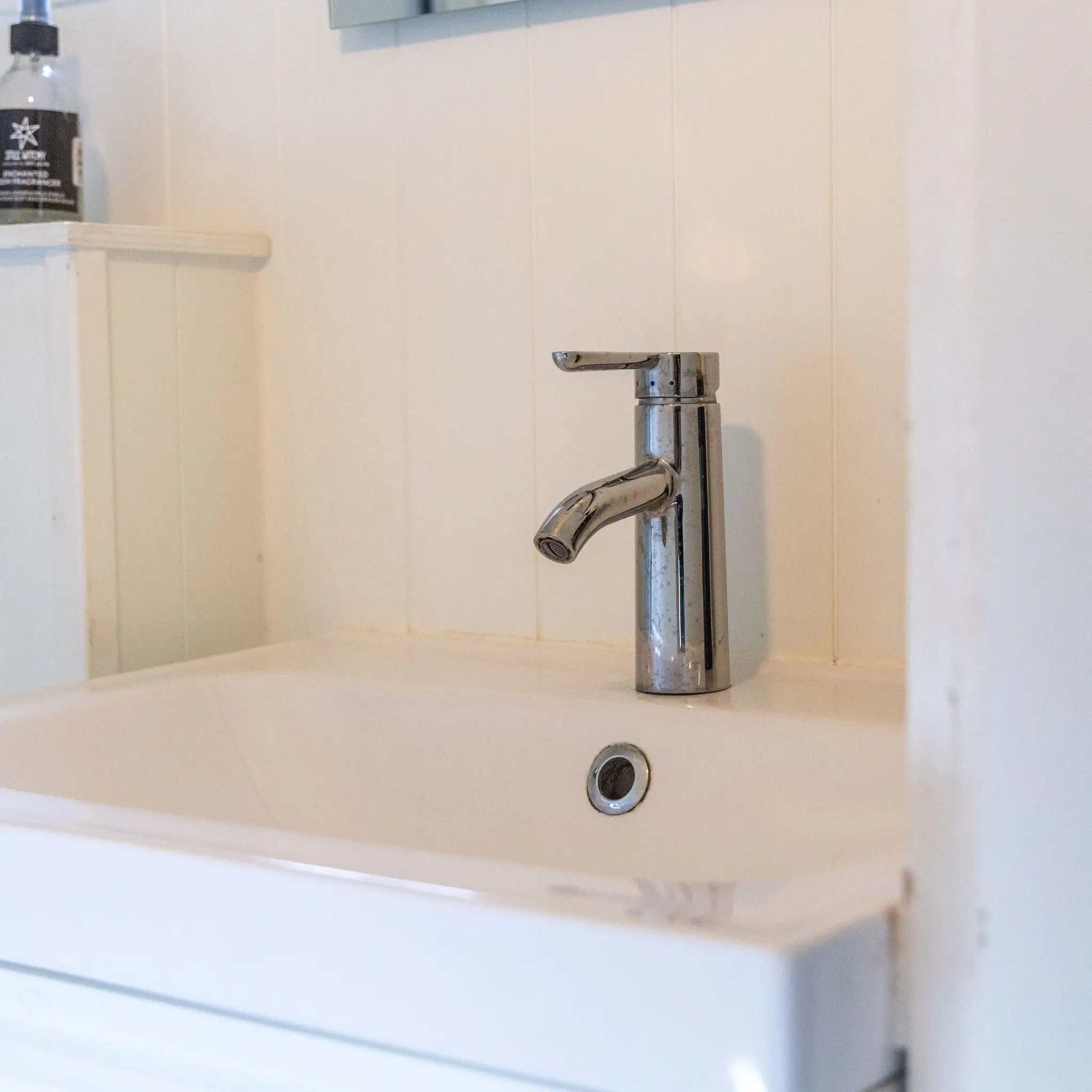 Bathroom sink close-up inside a floating shepherd’s hut with minimalist vanity and chrome tap.