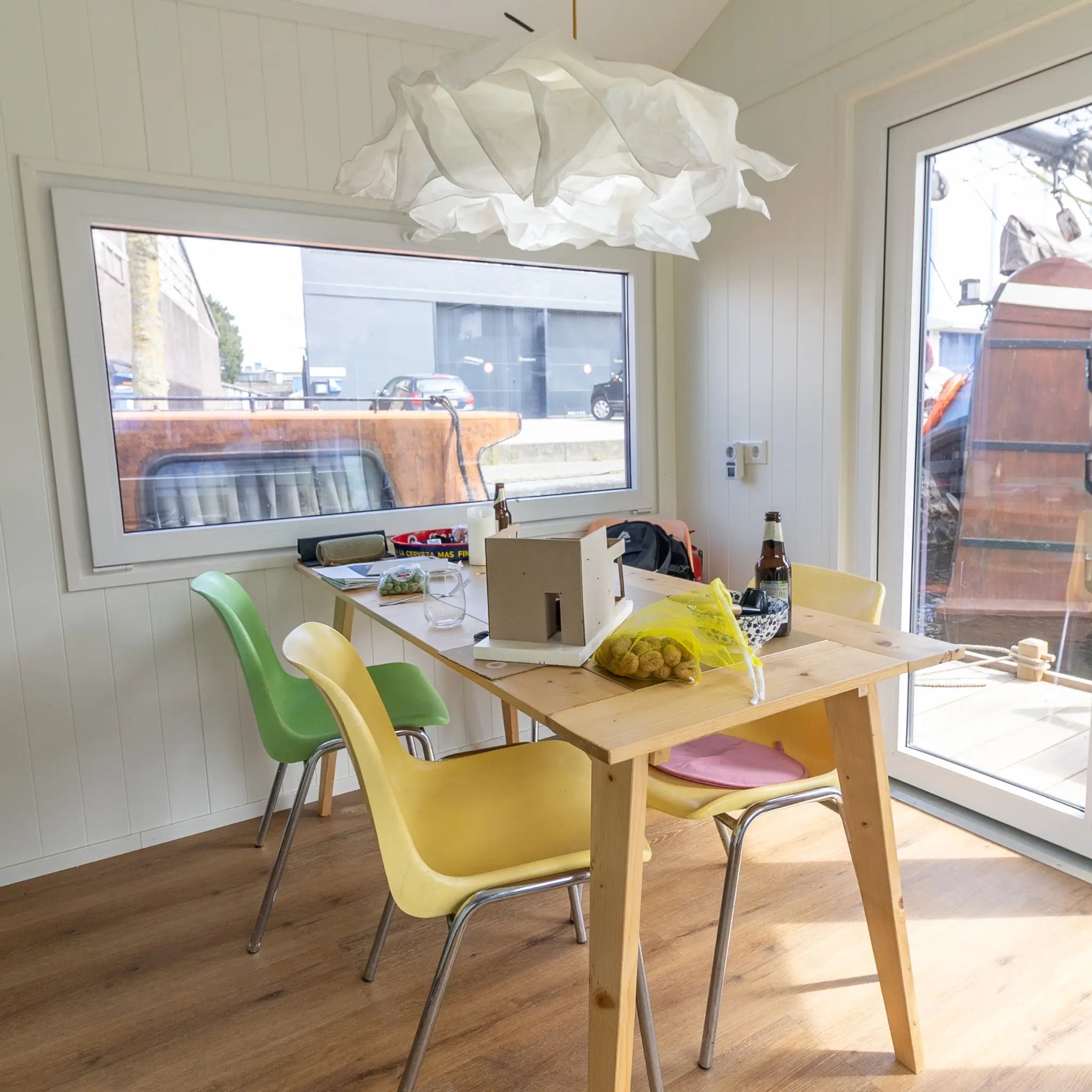 Dining space inside a floating shepherd’s hut with modern table setup, large windows and floating home interior.