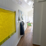 Hallway interior of a floating shepherd’s hut with wood flooring, white panelling and compact storage.