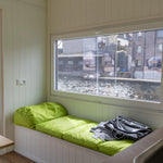 Window bench seating with bright green cushions and panoramic canal-side views.