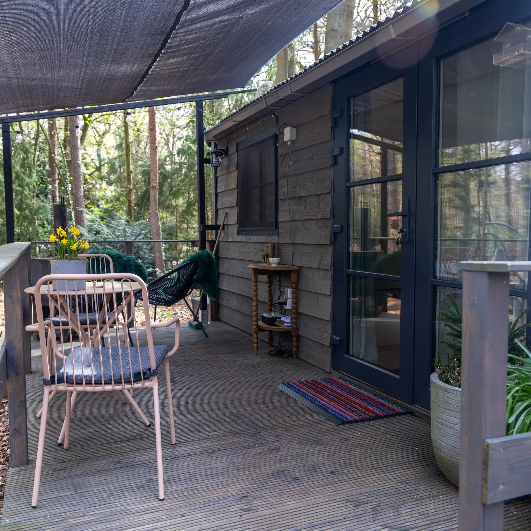 Woodland shepherd’s hut entrance with private decking, outdoor seating and covered terrace for a cosy 2 person glamping escape.