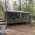 Stylish woodland shepherd’s hut with covered deck, outdoor seating and cosy forest retreat atmosphere.