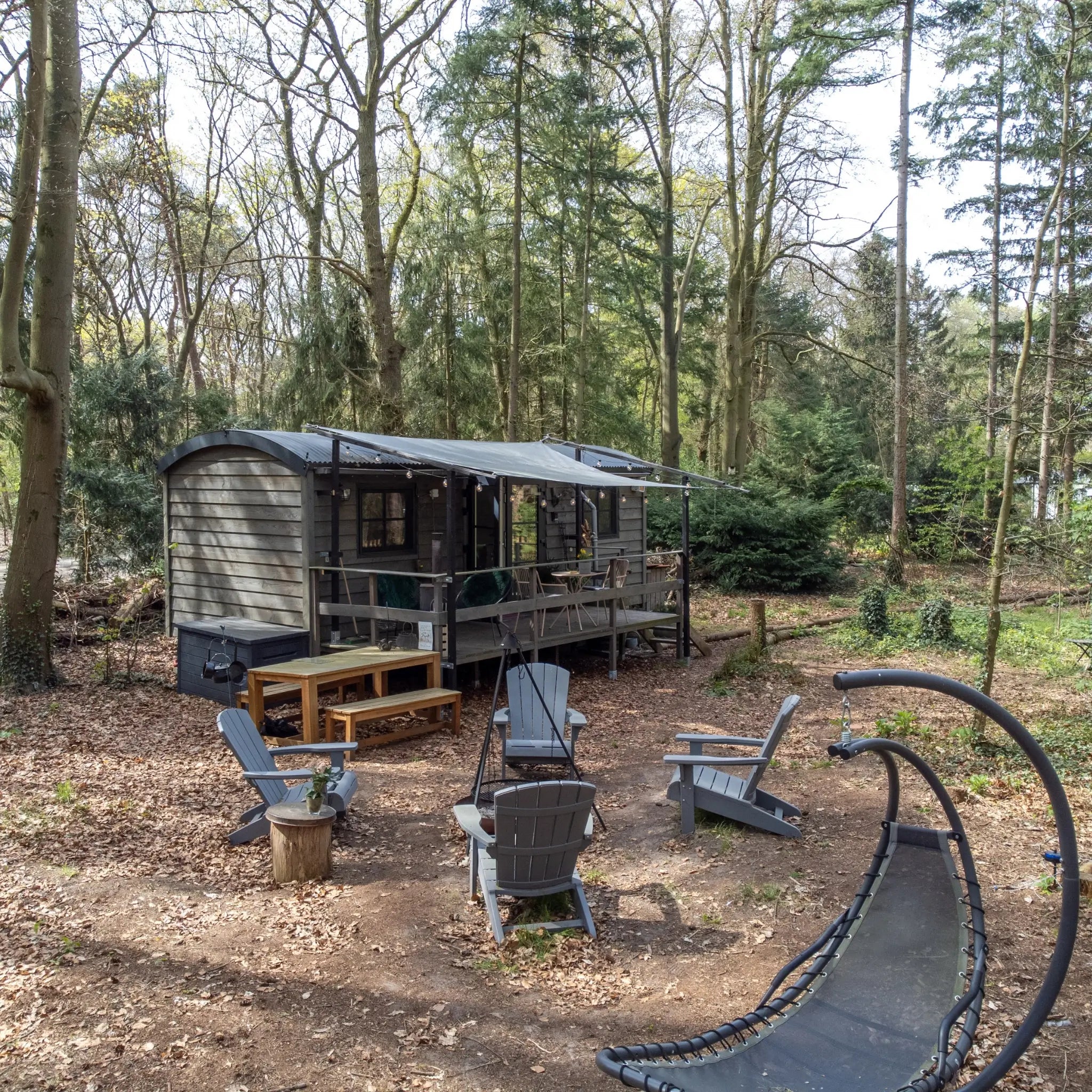 Woodland glamping shepherd’s hut with outdoor firepit seating area and peaceful forest escape setting.