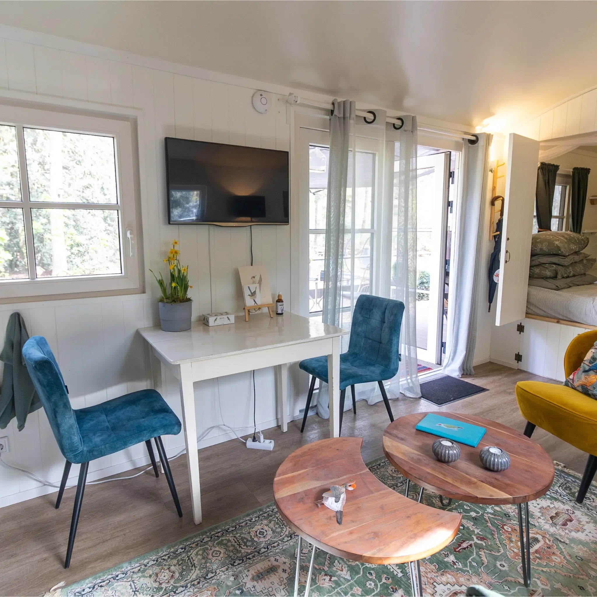 Bright dining and living area inside a modern shepherd’s hut with stylish seating and open-plan layout.