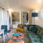 Open-plan shepherd’s hut interior with lounge area, kitchenette, bedroom entrance and cosy modern décor.