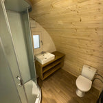 Full bathroom interior of the Dual Halfmoon Pod featuring shower enclosure, toilet, and wooden finishes