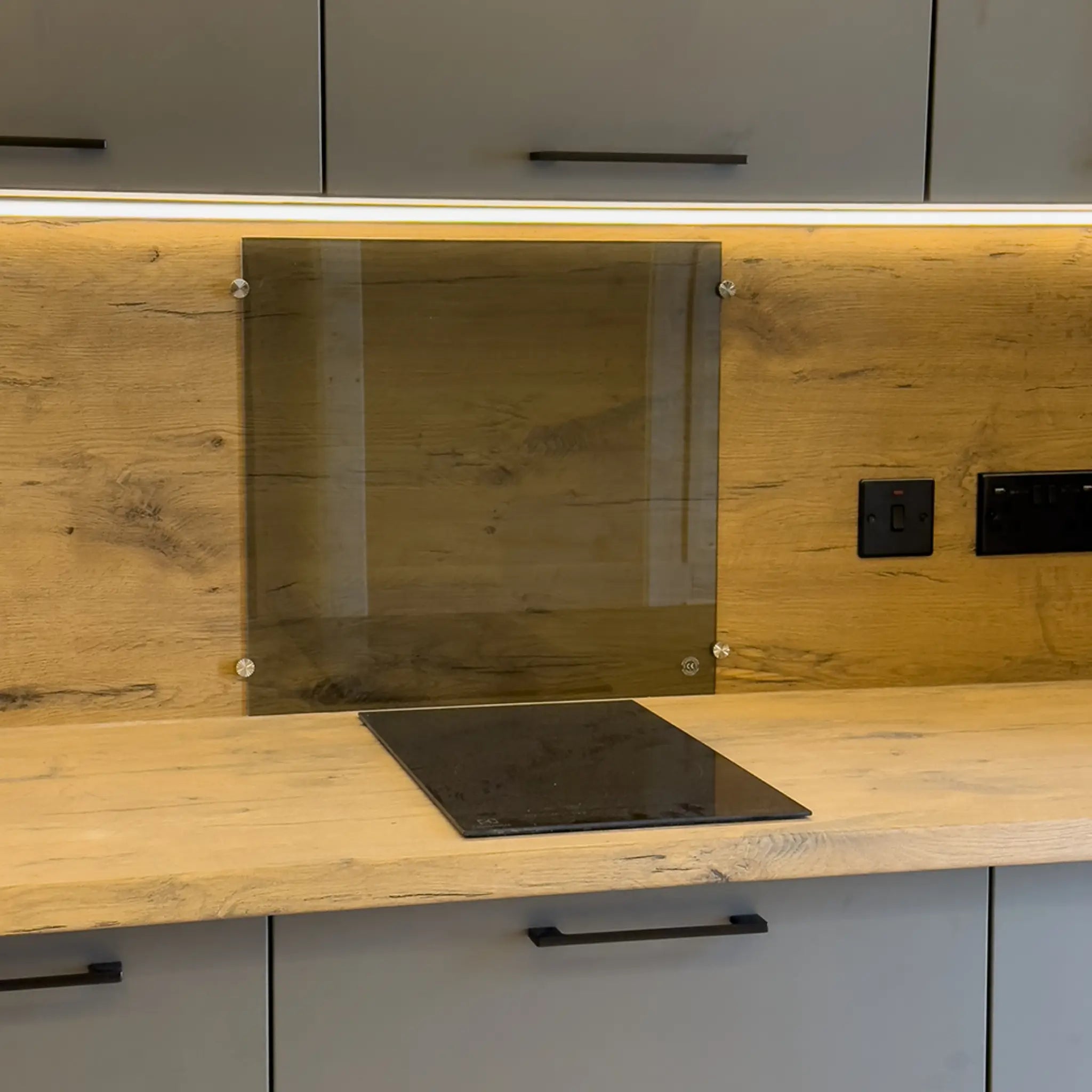 Close-up of induction hob and glass splashback on the wooden kitchen countertop