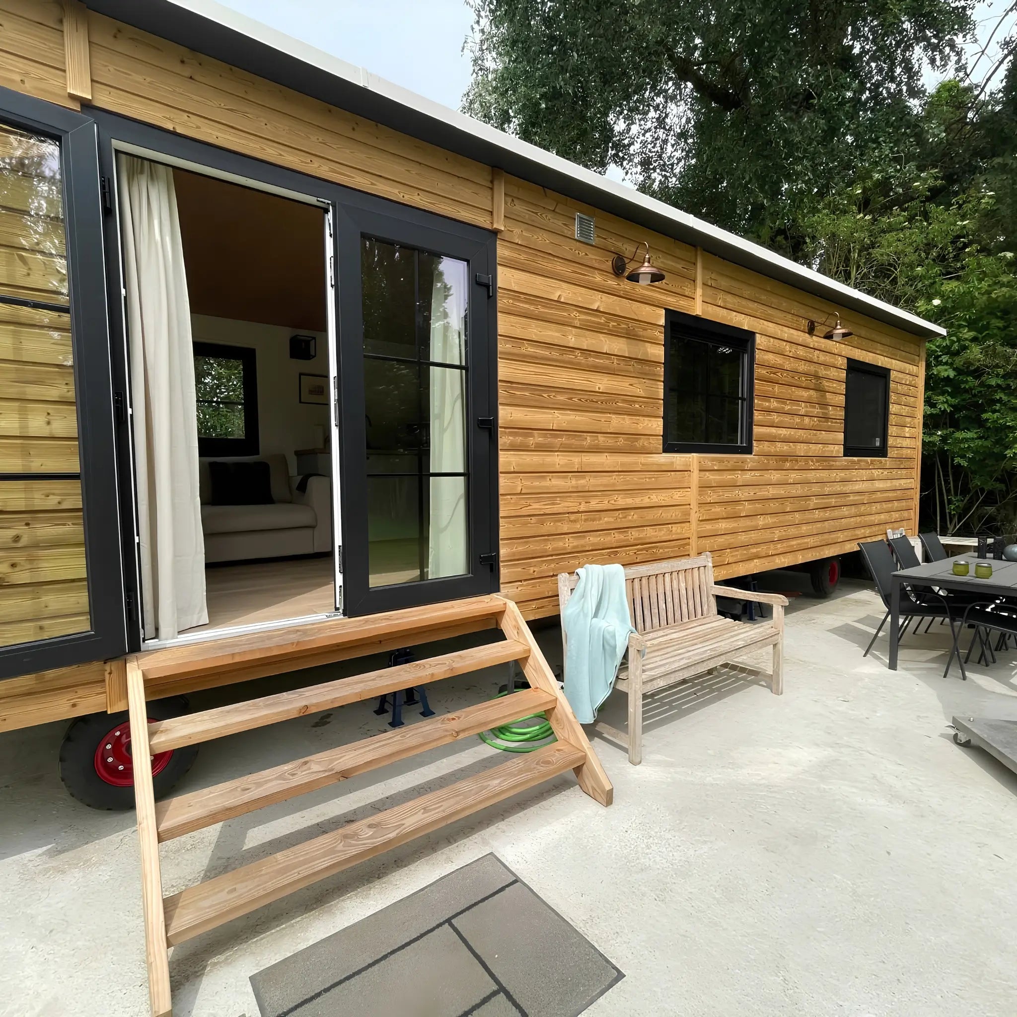 The Elmstead 2 Person Shepherd’s Hut exterior with timber cladding, black-framed French doors and entrance steps