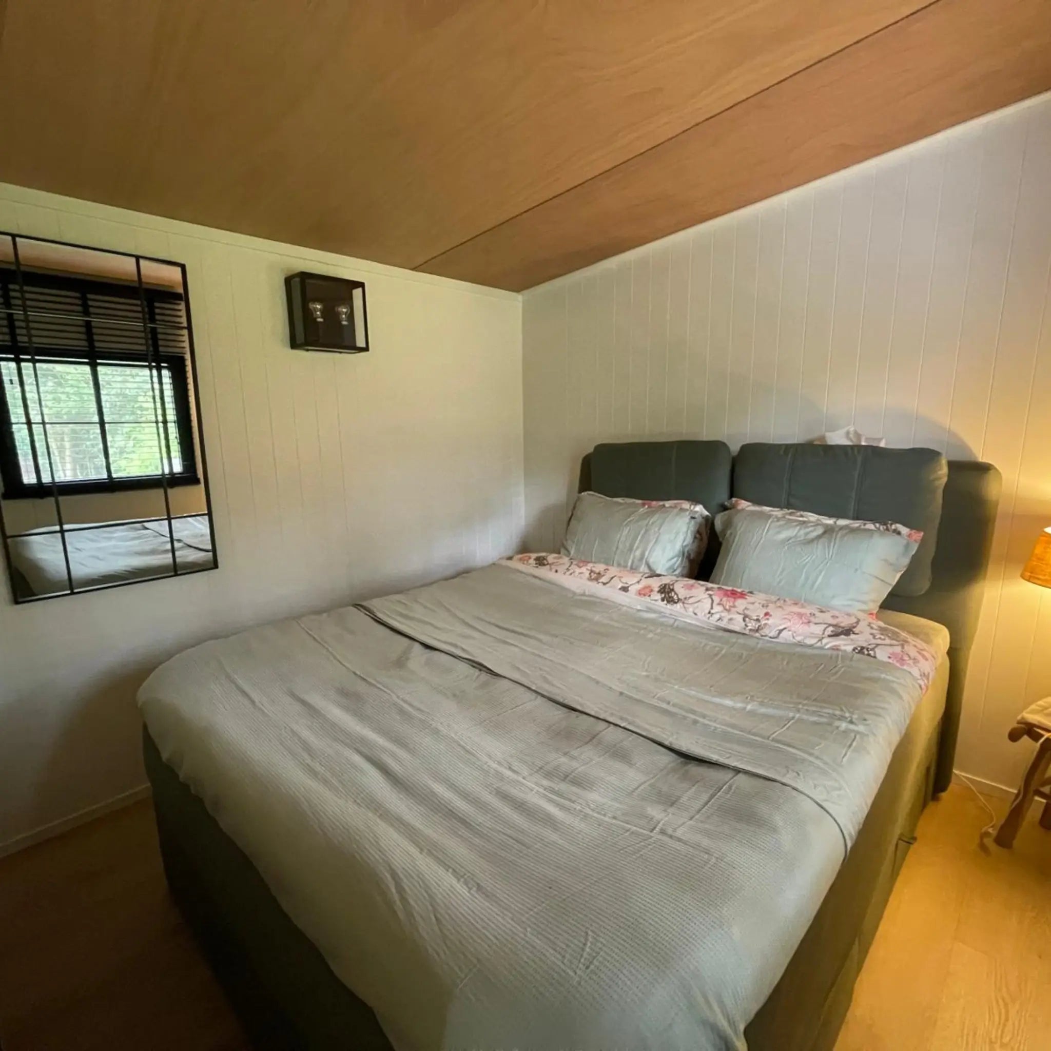 Cosy double bed inside The Elmstead 2 Person Shepherd’s Hut with timber ceiling and white panelled walls