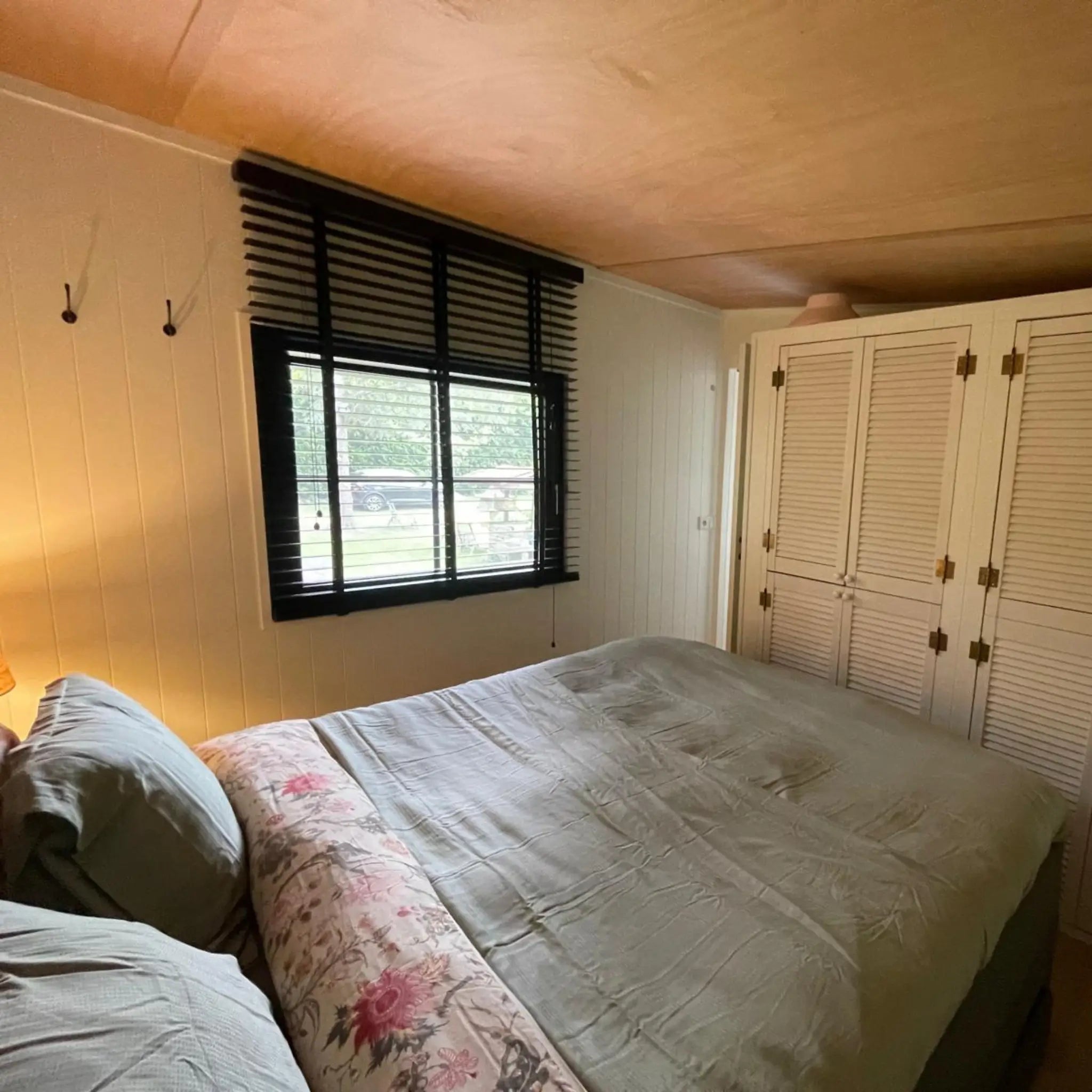 Double bedroom inside The Elmstead 2 Person Shepherd’s Hut with built-in wardrobes and black-framed window