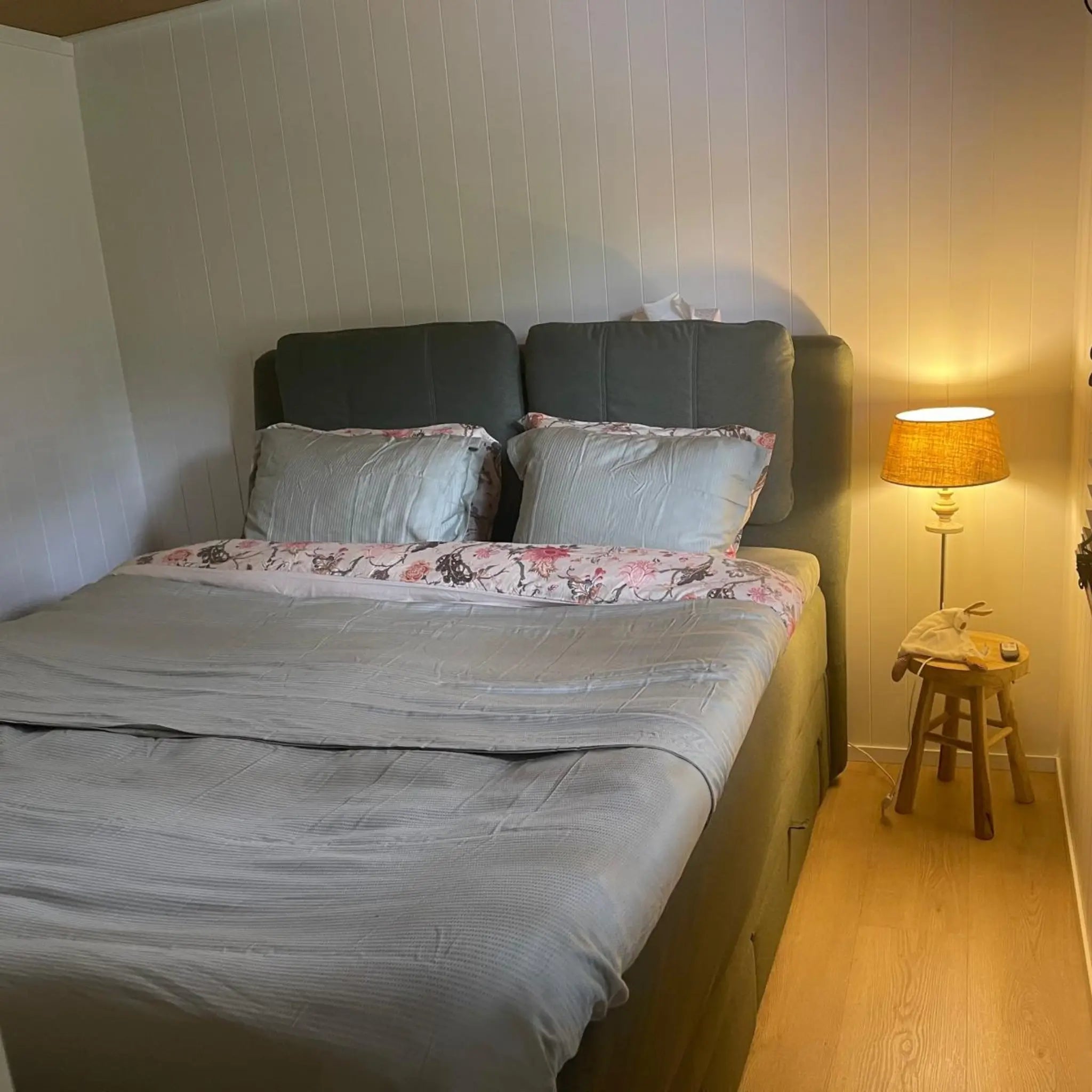 Double bedroom in The Elmstead 2 Person Shepherd’s Hut with upholstered bed, bedside lamp and light wood flooring