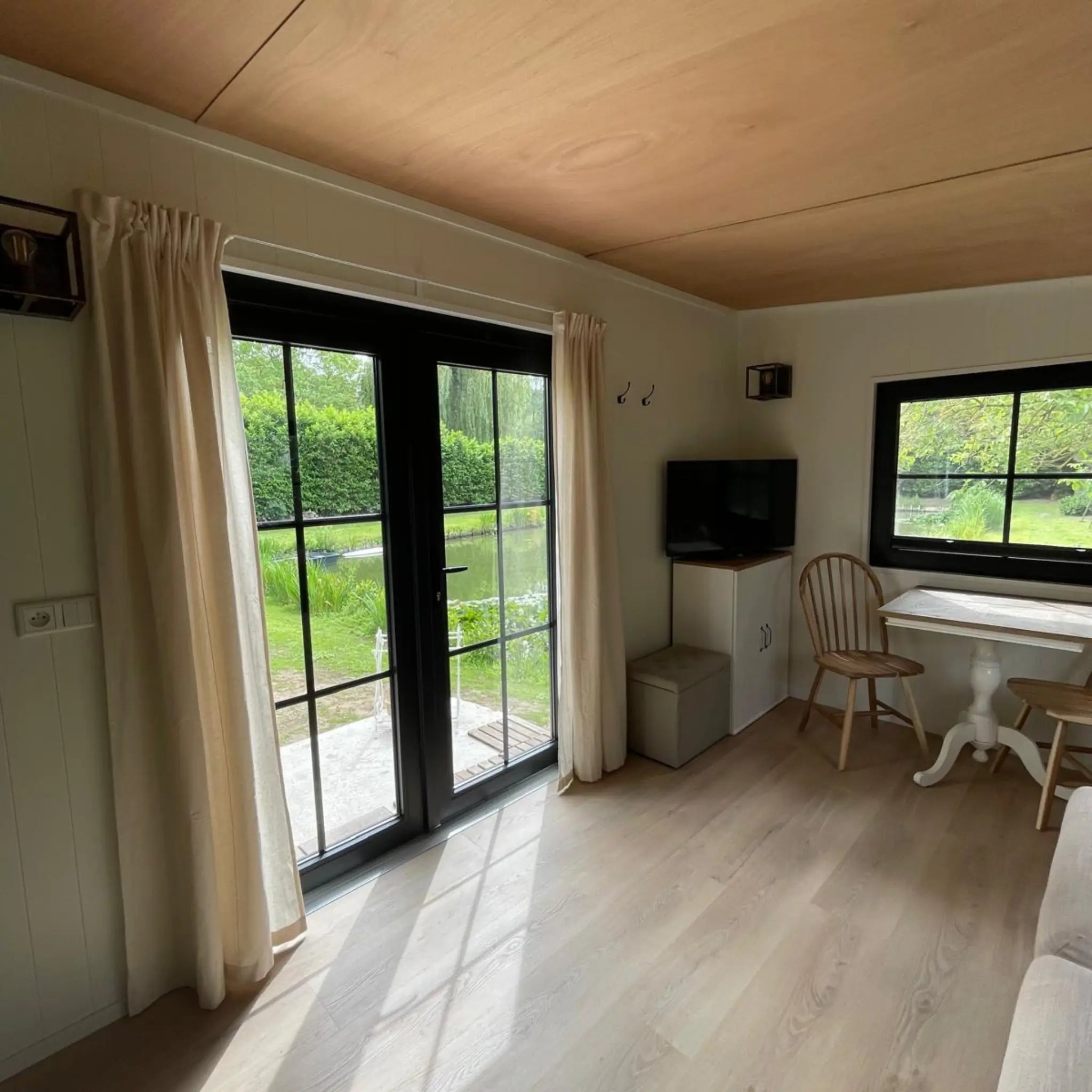 Bright living and dining area inside The Elmstead 2 Person Shepherd’s Hut with French doors, TV and countryside views