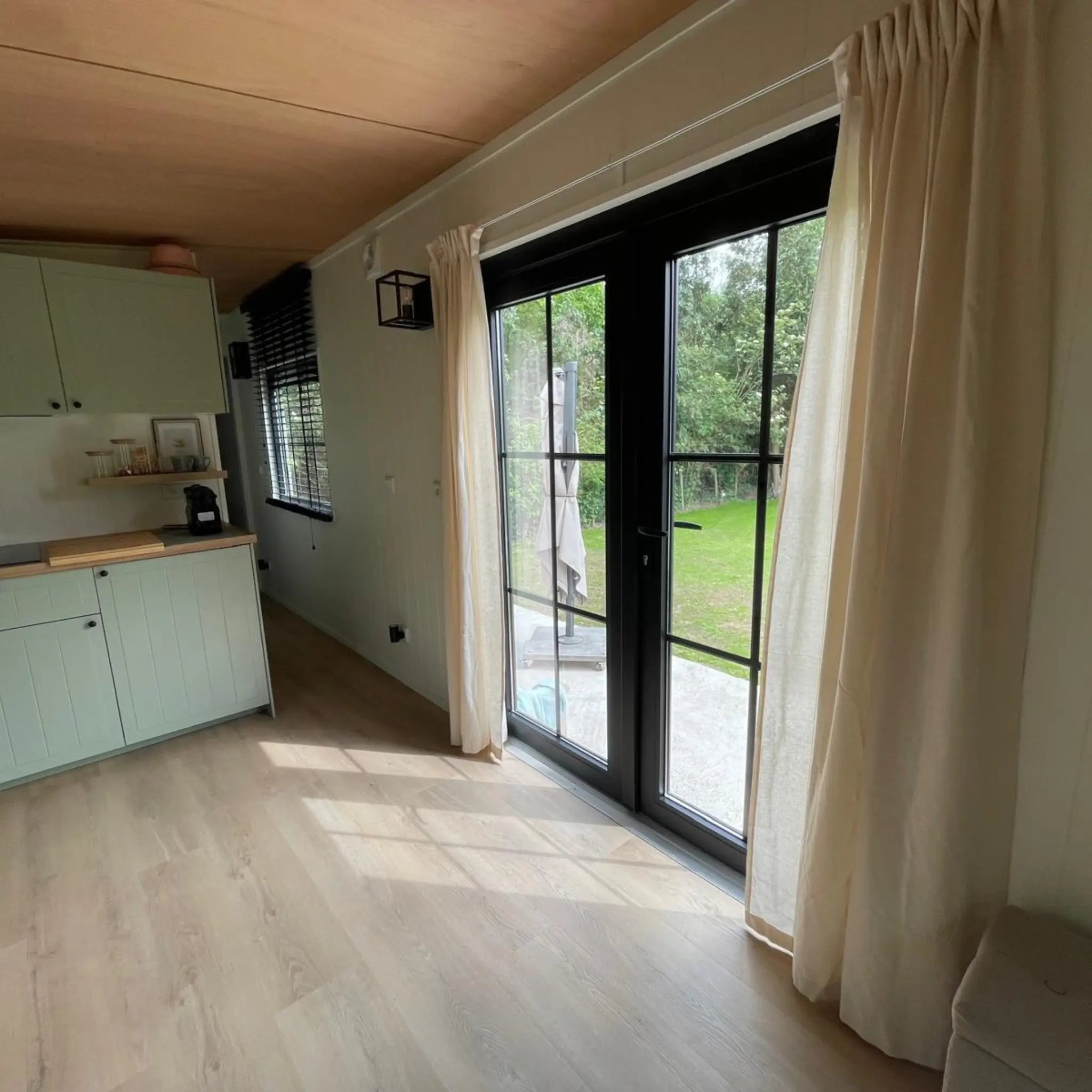Open-plan kitchen and living area in The Elmstead 2 Person Shepherd’s Hut with black-framed French doors