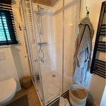 Modern shower enclosure inside The Elmstead 2 Person Shepherd’s Hut bathroom with heated towel rail