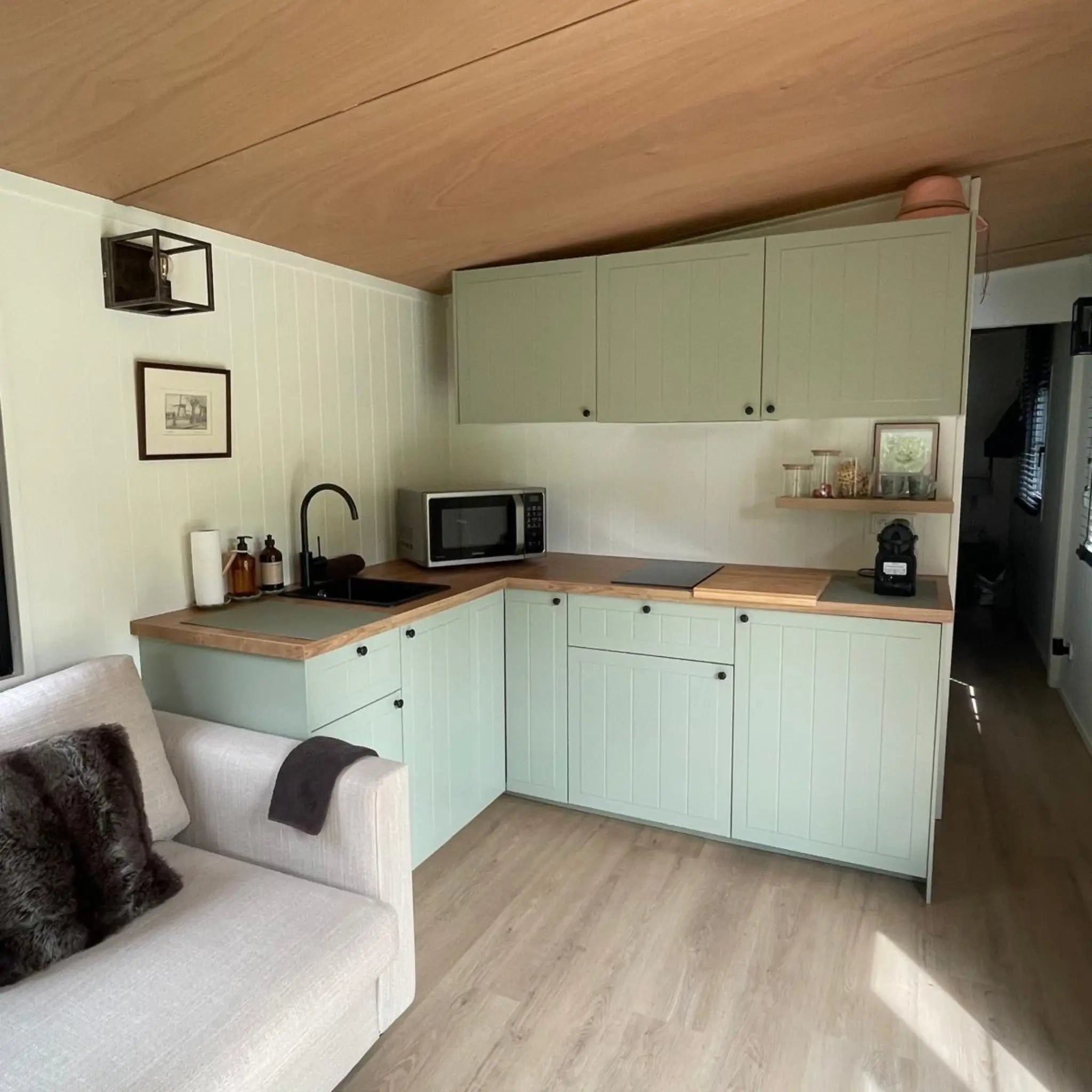 Sage green kitchen in The Elmstead 2 Person Shepherd’s Hut with integrated hob, microwave and timber worktops