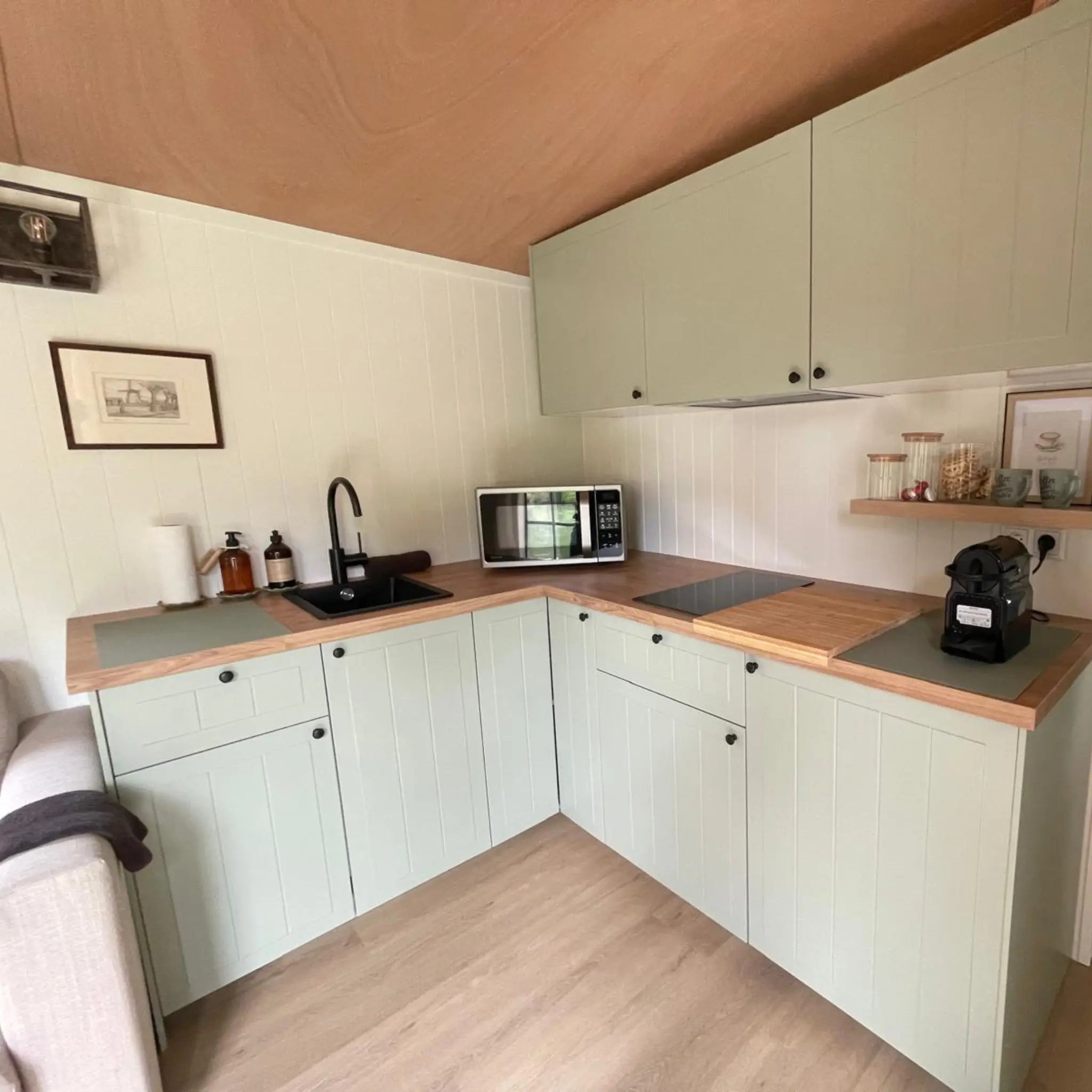 Fitted kitchen inside The Elmstead 2 Person Shepherd’s Hut with sage green cabinets, timber worktops and black sink