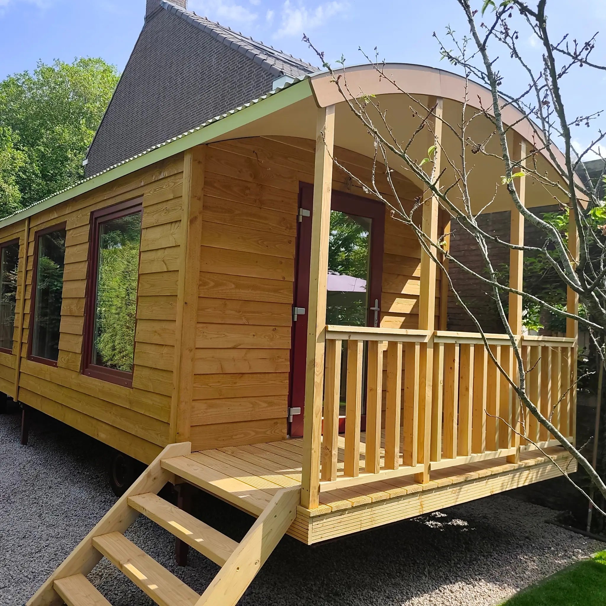 Exterior of The “Fernwood” Art Studio with timber cladding, large windows, covered entrance deck and curved roof