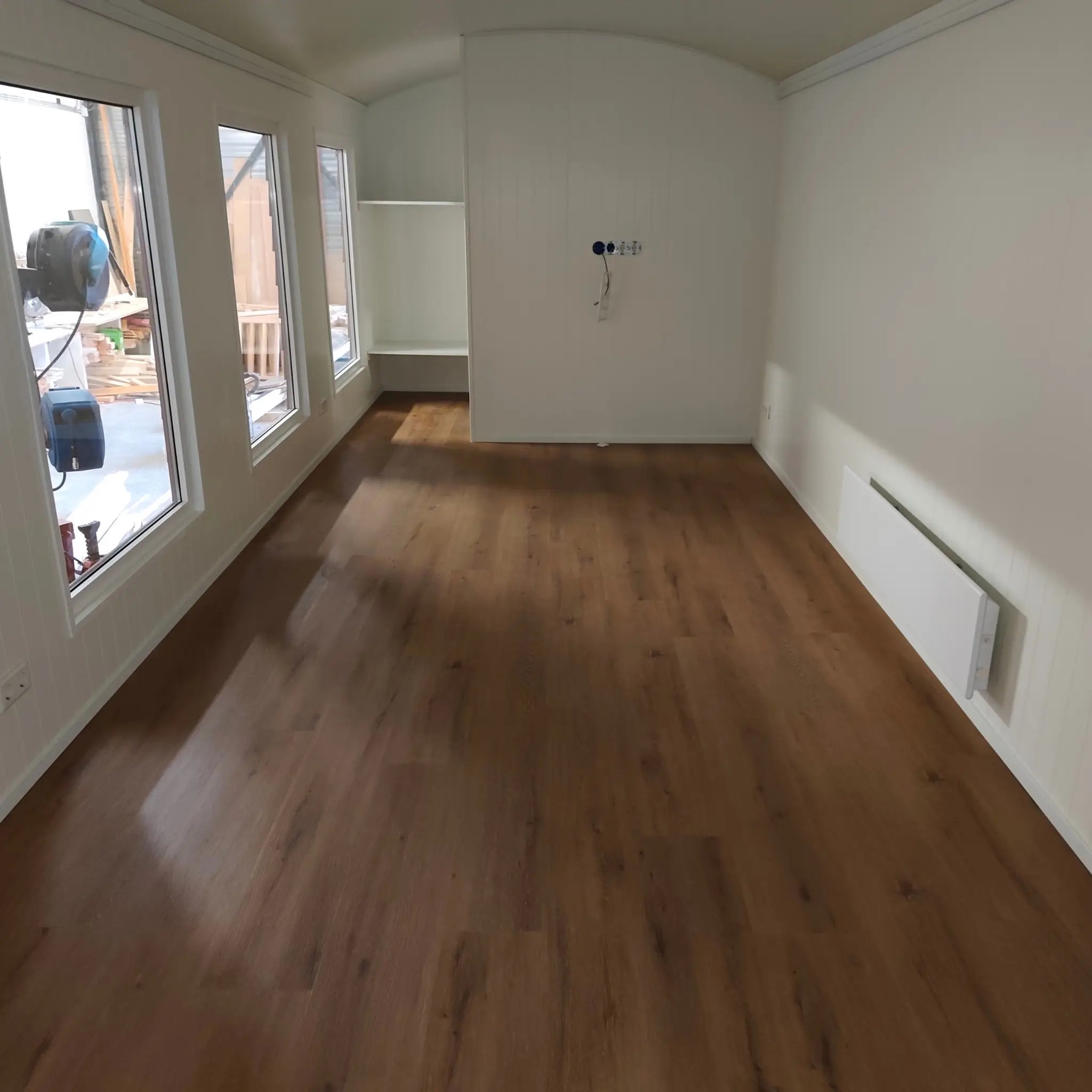 Unfurnished interior of The “Fernwood” Art Studio showing large windows, open workspace and wood-effect flooring