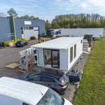Elevated front aerial view of contemporary floating shepherd’s hut with entrance decking and modern modular design.