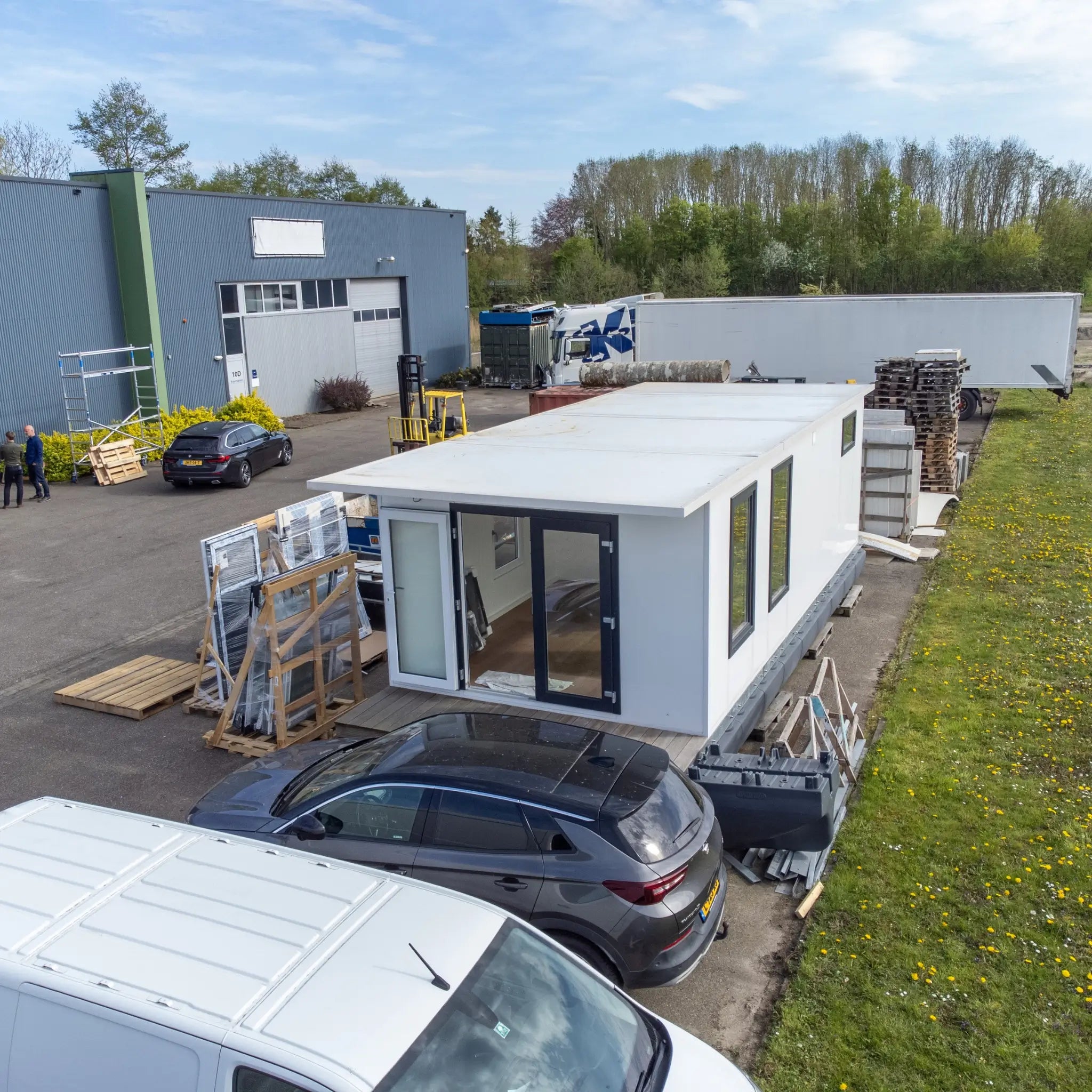 Elevated front aerial view of contemporary floating shepherd’s hut with entrance decking and modern modular design.