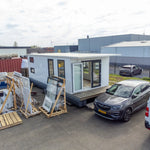 Elevated side exterior view of luxury floating shepherd’s hut with panoramic windows and compact waterside accommodation styling.