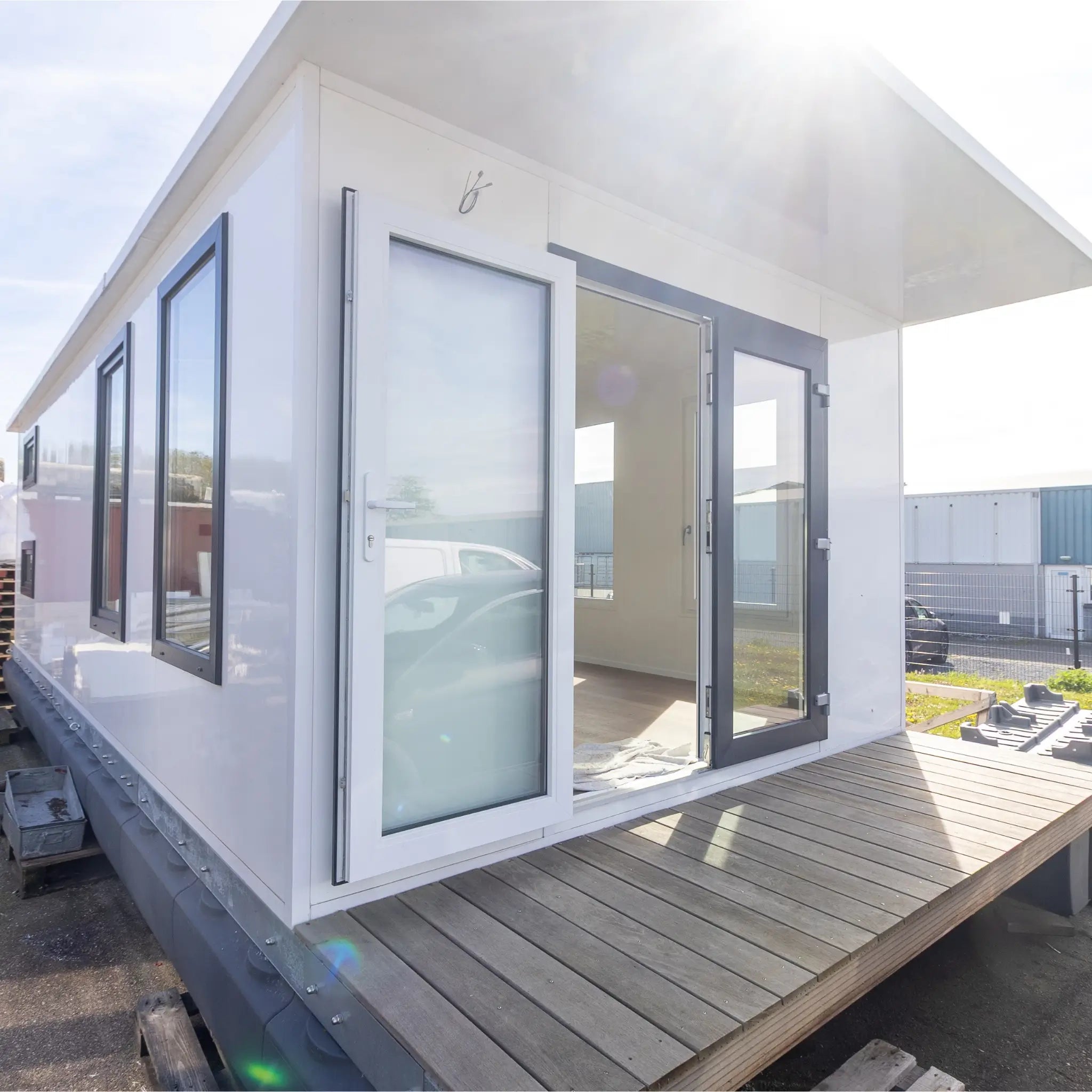 Close-up front exterior of modern floating shepherd’s hut with covered decking and large contemporary glass doors.