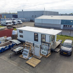 Elevated aerial side view of floating shepherd’s hut with compact modular design and timber decking entrance.