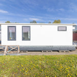 Angled exterior view of floating shepherd’s hut with covered decking, large patio doors, and contemporary tiny home styling.