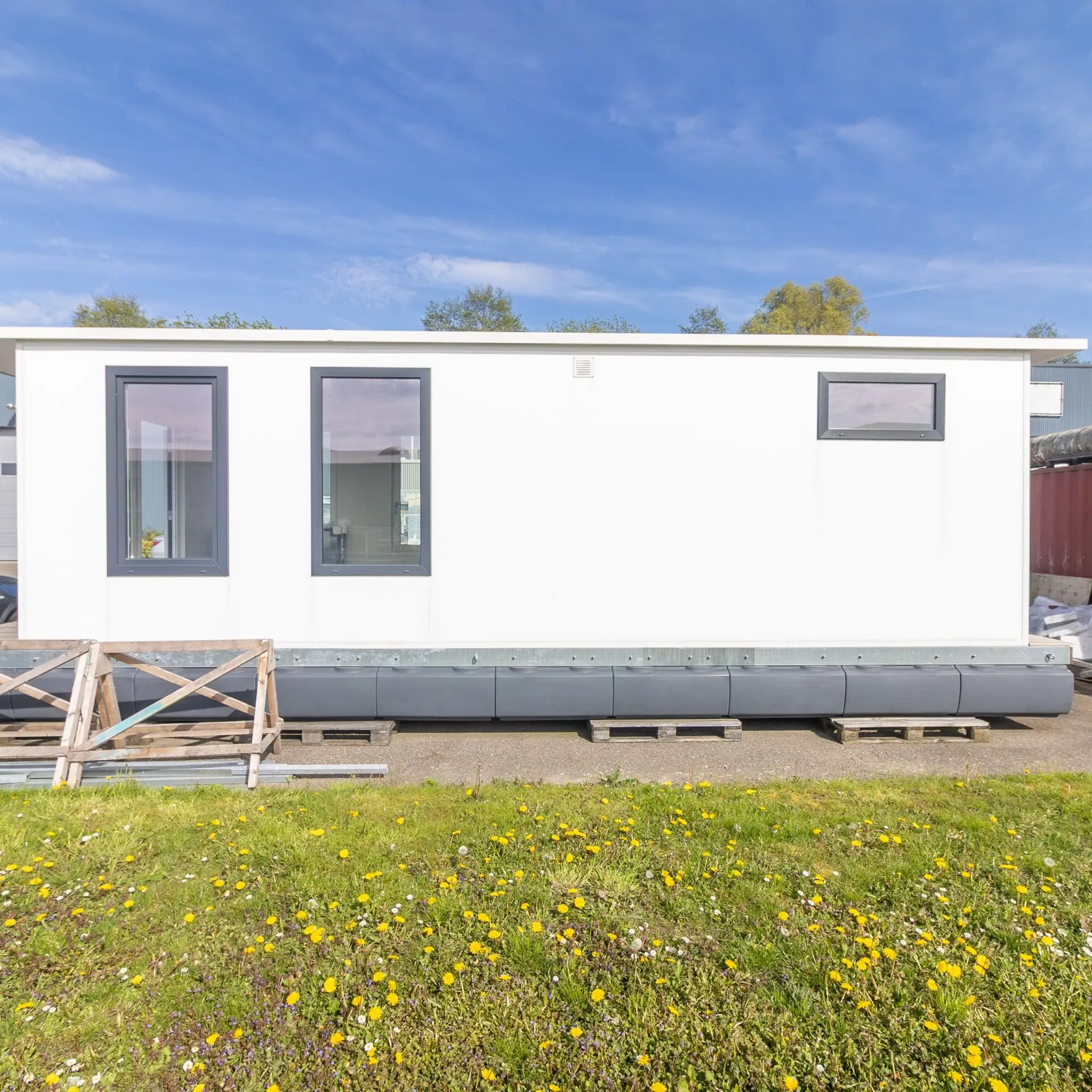 Angled exterior view of floating shepherd’s hut with covered decking, large patio doors, and contemporary tiny home styling.