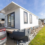 Close-up side exterior of luxury floating shepherd’s hut with modern framed windows and sleek white finish.