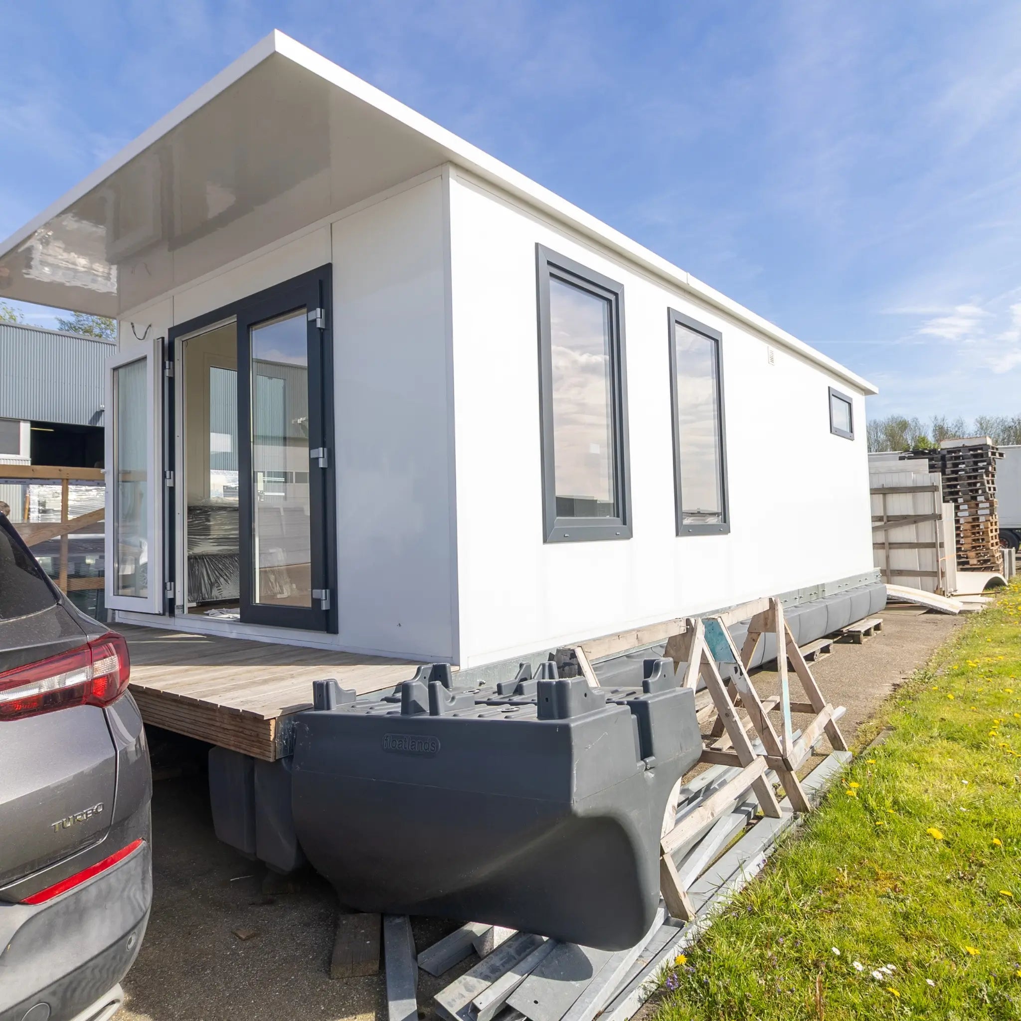 Close-up side exterior of luxury floating shepherd’s hut with modern framed windows and sleek white finish.
